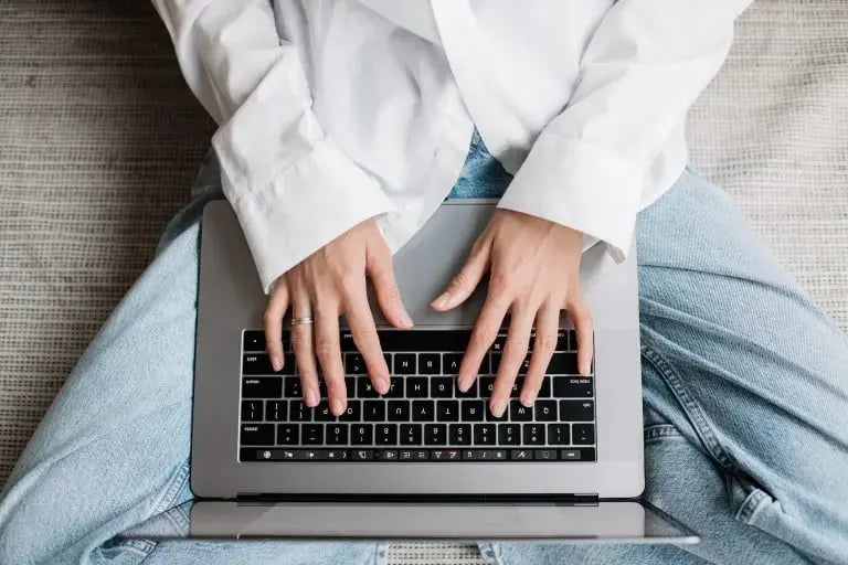 Une femme assise jambes croisées, avec un ordinateur portable sur les placer sur les jambes